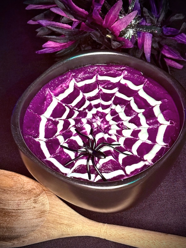 purple potato soup topped with a spider web design